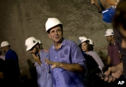 FILE - Rio de Janeiro's Mayor Eduardo Paes, center, talks with the media inside the Expressway Tunnel in Rio de Janeiro, Brazil, March 24, 2015.