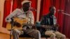 Zimbabwe music icon Oliver 'Tuku' Mtukudzi (L) plays his guitar during a rehearsal with a group of young musicians who are incubated at his Pakare Paye Arts and Music Centre in Norton 45km from the country's capital city Harare on January 12, 2018. / AFP PHOTO / Jekesai NJIKIZAN