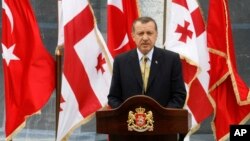 With Georgian and Turkish flags in the background, Turkish Prime Minister Recep Tayyip Erdogan speaks at a news conference in Tbilisi, Georgia, Aug. 14. 2008.