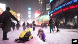 Anak-anak bermain salju di Times Square, New York (2/1). 
