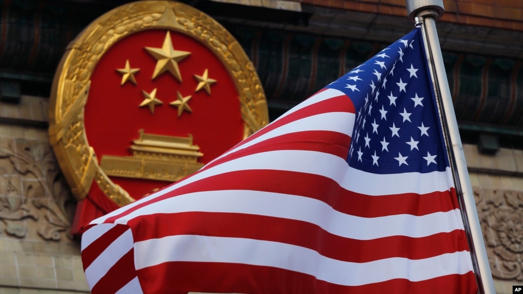 FILE - An American flag is flown next to the Chinese national emblem.