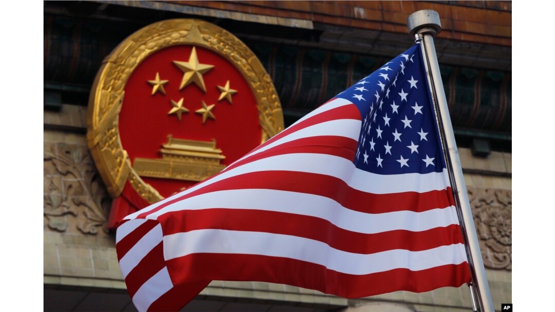 FILE - An American flag is flown next to the Chinese national emblem during a welcome ceremony for visiting U.S. President Donald Trump outside the Great Hall of the People in Beijing, Nov. 9, 2017.