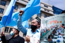 FILE - Demonstrators from the Uyghur community gesture as they take part in a protest near the Belgium parliament in Brussels, July 8, 2021.