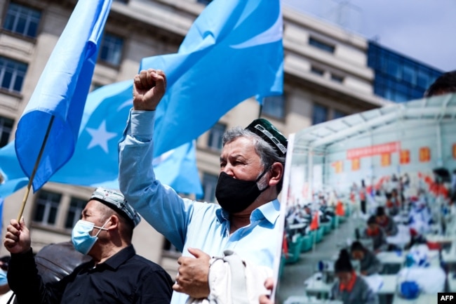 FILE - Demonstrators from the Uyghur community gesture as they take part in a protest near the Belgium parliament in Brussels, July 8, 2021.