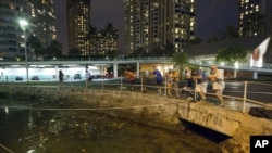 Visitors and Oahu residents watch the water level in the Ala Wai Harbor waiting for the arrival of a tsunami Saturday, Oct. 27, 2012, in Honolulu. 