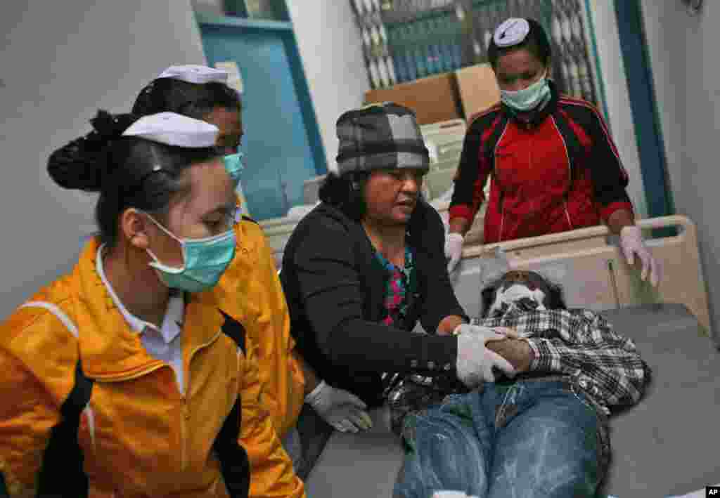 Nurses dress a victim of the eruption of Mount Sinabung for burial at a hospital in Kabanjahe, North Sumatra, Indonesia, Feb. 1, 2014.