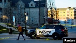 A person walks past a police car blocking Main Street the morning after a car ploughed through a holiday parade in Waukesha, Wisconsin, Nov. 22, 2021.