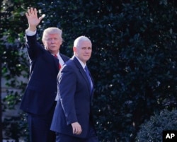 FILE - President Donald Trump, accompanied by Vice President Mike Pence, left, waves to members of the media as they walk to the Oval Office of the White House in Washington, Jan. 25, 2017.