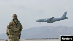 Un soldado hace vigilancia mientras un avión militar aterriza en una base militar en Kandahar, Afganistán. Muchas bases impplmenetarán medidas para prevenir más contagios de coronavirus. Foto Reuters