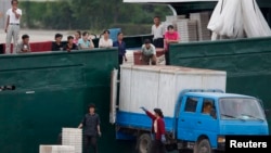 Северокорейские рабочие грузят продукцию в грузовик (архивное фото)