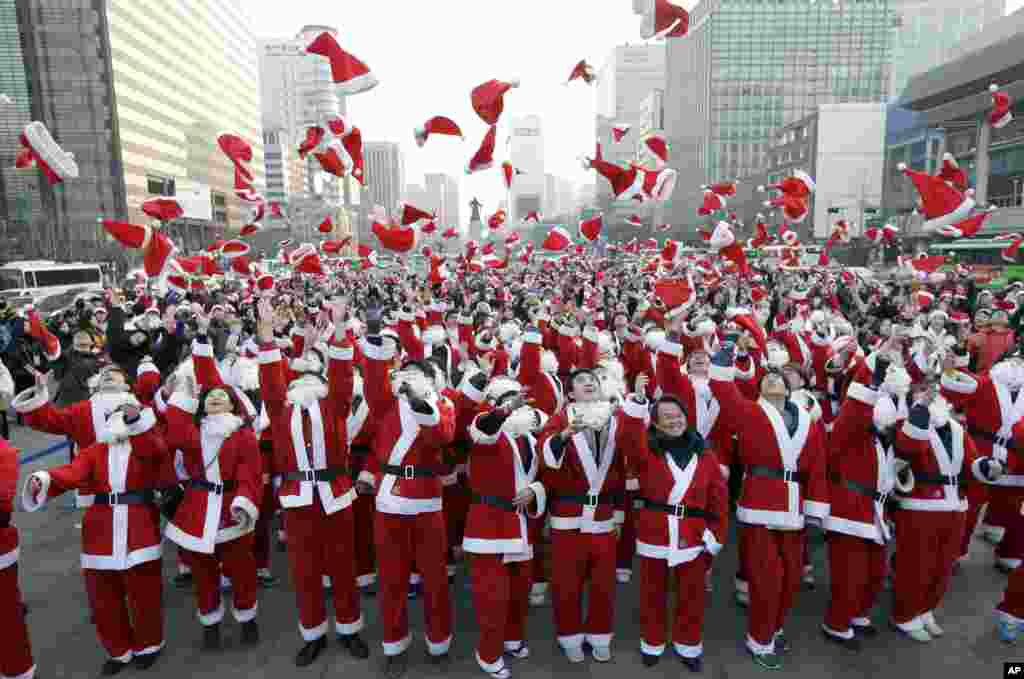 More than 1,000 volunteers clad in Santa Claus costumes throw their hats in the air as they gather to deliver gifts for the poor in downtown Seoul, Dec. 24, 2013. 