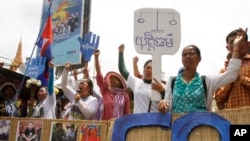 Supporters shout slogans on a blocked main street near the Phnom Penh Municipality Court during a gathering to call for the release of anti-government protesters who were arrested in a police crackdown, in Phnom Penh, Cambodia, Tuesday, May 6, 2014. Nearly two dozen of Cambodia's anti-government protesters were arrested earlier this year in connection with social unrest. (AP Photo/Heng Sinith)