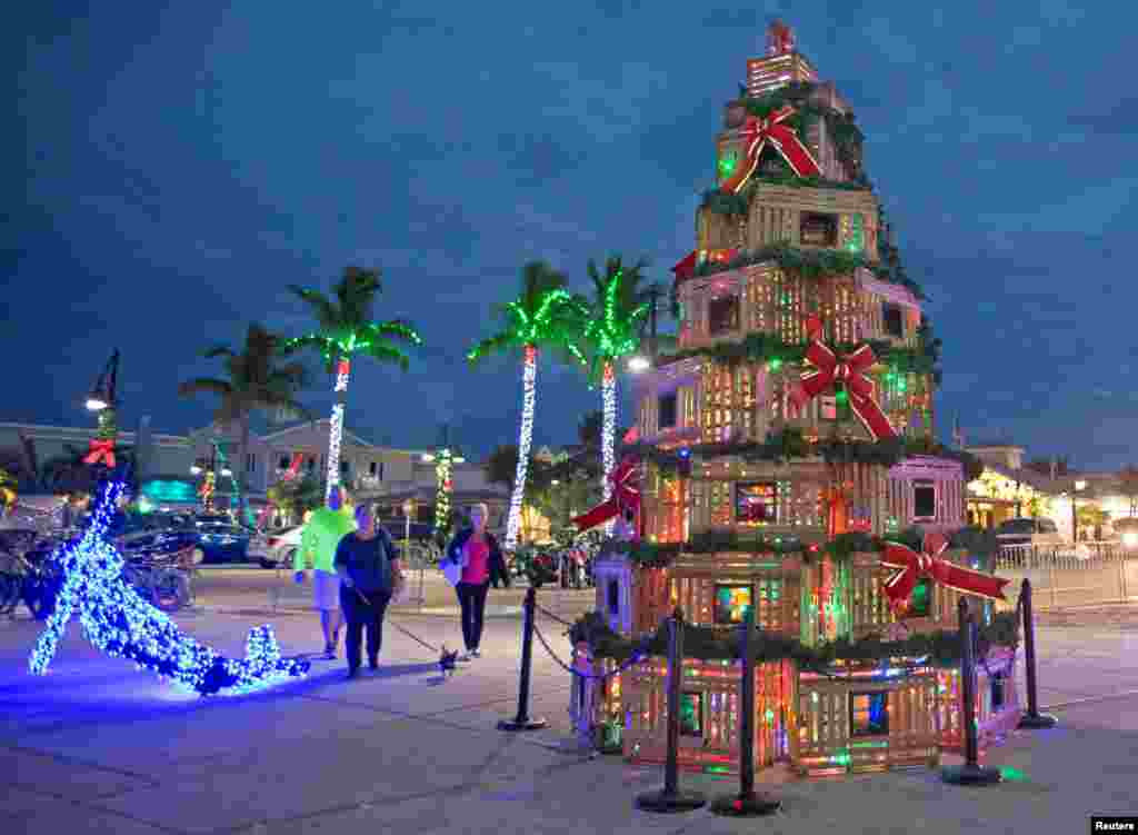 People walk past lobster traps stacked in the shape of a Christmas tree at the Historic Seaport in Key West, Florida, U.S., Nov. 29, 2018. (Carol Tedesco/Florida Keys News Bureau/Handout).