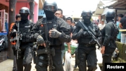 FILE - Armed anti-terror police walk ahead of guard officers in March 2015 after searching the house of a man suspected of being involved in Islamic State-related activities in Indonesia's Banten province.