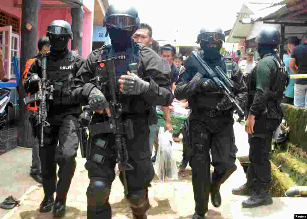 เจ้าหน้าที่ตำรวจต่อต้านการก่อการร้ายติดอาวุธ เดินให้การอารักขาเจ้าหน้าที่กลุ่มหนึ่งที่เดินถือถุงใส่หลักฐานจากบ้านของผู้ต้องสงสัยคนหนึ่งว่ามีส่วนเกี่ยวข้องกับกลุ่มรัฐอิสลามทางตอนใต้เมือง Tangerang จังหวัด Banten ประเทศอินโดนีเซีย
