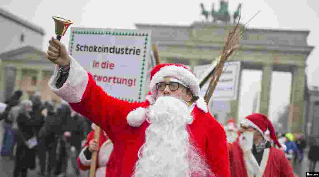 Các nhà hoạt động trong trang phục ông già Noel trong một chiến dịch thu hút sự chú ý tới những vi phạm nhân quyền tại các nông trại trồng ca cao ở Tây Phi, trước cổng Brandenburg ở Berlin, Đức.