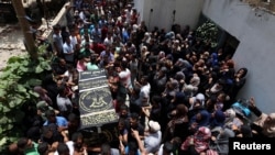 Mourners carry a casket containing the body of a Palestinian Islamic Jihad militant, who was killed in Israeli tank shelling, during his funeral in the southern Gaza Strip, May 27, 2018. 