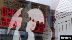 FILE - A board displaying currency exchange rates is reflected in a shop window in central Moscow, August 29, 2014.