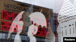 FILE - A board displaying currency exchange rates is reflected in a shop window in central Moscow, August 29, 2014.