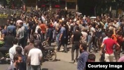 Pasukan keamanan Iran (berpakaian hitam) menghadapi demonstran anti-pemerintah di kota terbesar ke-3 Iran, Isfahan, dalam aksi protes yang dimulai sejak 31 Juli 2018 dan berlanjut untuk hari kedua pada 1 Agustus. (Foto courtesy: Radio Farda)
