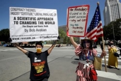 Protesters argue opposing views during a rally calling for an end to Gov. Gavin Newsom's stay-at-home orders amid the COVID-19 pandemic Wednesday, April 22, 2020, outside of city hall in downtown Los Angeles. (AP Photo/Marcio Jose Sanchez)