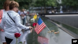 Para pengunjung menyentuh nama-nama korban tewas dalam serangan terhadap gedung World Trade Center di kota New York, 11 September 2001 (11/9). 