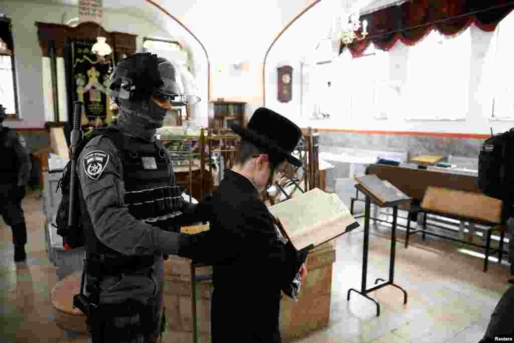 An Israeli policeman removes an ultra-Orthodox Jewish youth from a synagogue as they enforce restrictions of a partial lockdown against the coronavirus disease (COVID-19) in Mea Shearim neighborhood of Jerusalem, March 30, 2020.