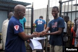 FILE - Cassius Kollie (R), 24, receives a certificate for being cured of Ebola in Paynesville, Liberia, July 20, 2015.