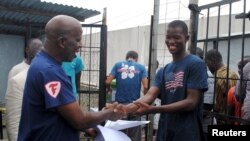 FILE - Cassius Kollie (R), 24, one of four people discharged from an Ebola treatment unit, receives a certificate for being cured of the disease in Paynesville, Liberia, July 20, 2015. 