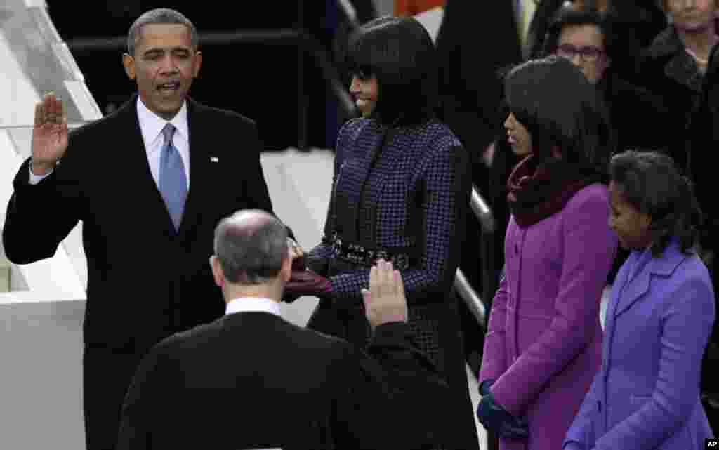 Presiden Barack Obama mengambil sumpah jabatan dari Ketua Mahkamah Agung John Roberts di gedung U.S. Capitol pada inaugurasi presiden ke-57 di Washington, Senin (21/1), didampingi ibu negara Michelle Obama dan putri mereka Malia dan Sasha. (AP/Evan Vucci)