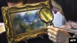 An art shopper looks closely at a 5.5 inch by 6.6 inch painting by French Impressionist master Pierre-Auguste Renoir in Alexandria, Virginia, September 25, 2012. 