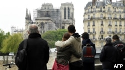 People hug while looking at Notre-Dame-de-Paris in the aftermath of a fire that devastated the cathedral, April 16, 2019. 