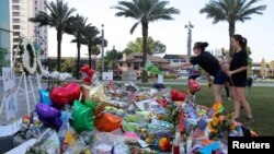 A woman throws a bouquet of flowers at a memorial for the victims of the shooting at the Pulse gay nightclub in Orlando, Florida, June 14, 2016.