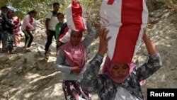 Residents affected by earthquake and tsunami carry aid provided during the visit of Indonesian President Joko Widodo in Donggala, north of Palu, Central Sulawesi, Indonesia, Oct. 3, 2018 in this photo taken by Antara Foto. 