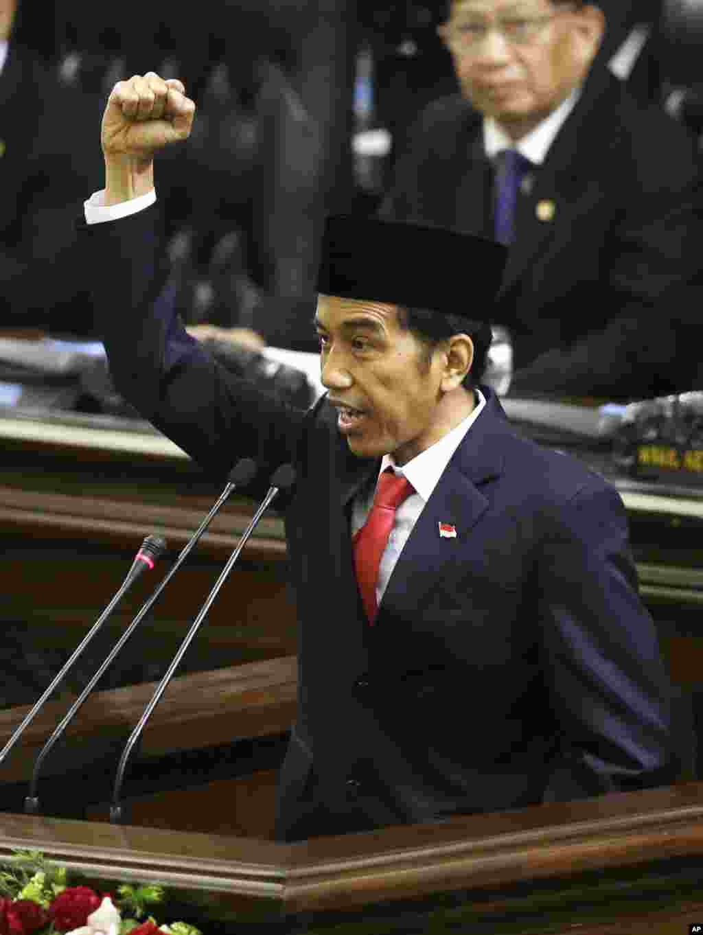 Presiden Joko Widodo mengacungkan tinju ke udara sambil berseru &quot;Merdeka!&quot; saat menutup pidato pelantikan di Gedung DPR, Senin (20/10).&nbsp;(AP/Dita Alangkara) 