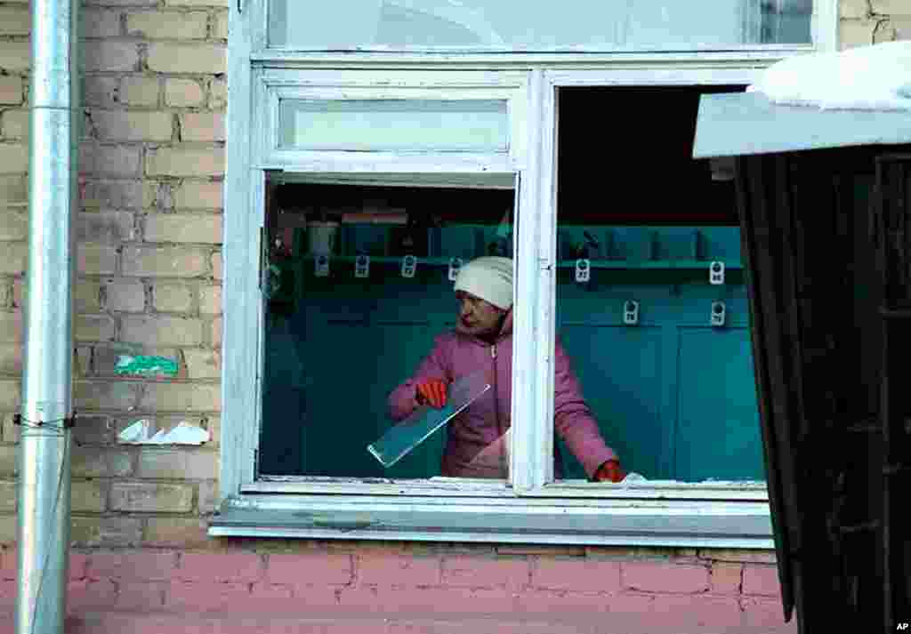 A woman cleans away glass debris from a window after the meteorite explosion, February 15, 2013. 
