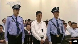 Mantan politisi China, Bo Xilai (tengah) diapit polisi saat menjalani sidang di pengadilan Jinan, propinsi Shandong, China (22/8).