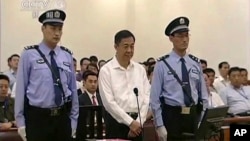In this image taken from video, disgraced politician Bo Xilai, center, stands in the courtroom, flanked by police guards at Jinan Intermediate People's Court in eastern China's Shandong province, Aug. 22, 2013.