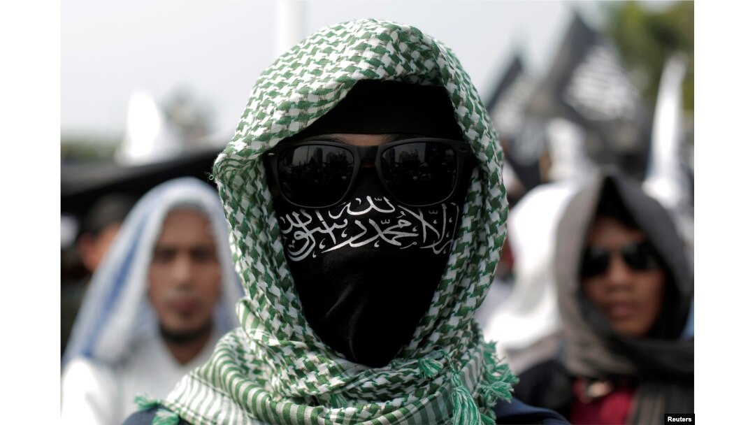 An Islamic group member covers his face with Hizbut Tahrir flag during a protest against the decree allowing the government to disband organizations deemed to run counter to the secular state, in Jakarta, Indonesia, July 28, 2017.