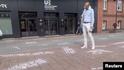 A man takes pictures of 'hate tweets,' part of the art project "#HEYTWITTER" created by Shahak Shapira, outside Twitter office in Hamburg, Germany, Aug. 4, 2017, in this picture obtained from social media.