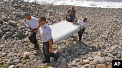 Polisi Perancis menggotong potongan pesawat di Saint-Andre, Pulau Reunion (29/7). (AP/Lucas Marie)