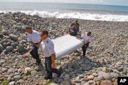 FILE - French police officers carry a piece of debris from a plane in Saint-Andre, Reunion Island, July 29, 2015.