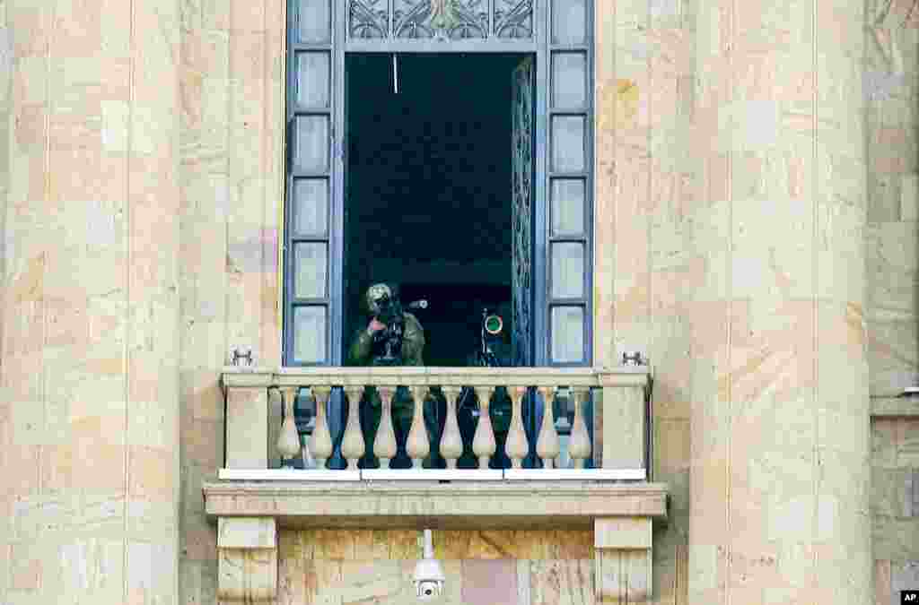A security agent points a sniper rifle from a window of the Parliament building as opposition demonstrators rally to pressure Armenian Prime Minister Nikol Pashinyan to resign in Yerevan, Armenia.