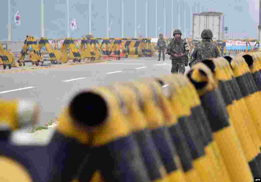 South Korean soldiers walk by barricades on the road leading to North Korea&#39;s Kaesong joint industrial complex at a military checkpoint in the border city of Paju.&nbsp; Military tensions between the North and South soared following a rare exchange of artillery shells across their heavily fortified border on Thursday.