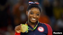 FILE - U.S. gymnast Simone Biles poses with her gold medal for artistic gymnastics during the victory ceremony at the Rio Olympic Arena in Rio de Janeiro, Brazil, Aug. 16, 2016. 