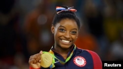 FILE - US gymnyst Simone Biles poses with her gold medal for artistic gymnastics during the victory ceremony at the Rio Olympic Arena in Rio de Janeiro, Brazil, Aug. 16, 2016.