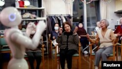 Residents follow moves made by humanoid robot 'Pepper' during an afternoon exercise routine at Shin-tomi nursing home in Tokyo, Feb. 2, 2018.