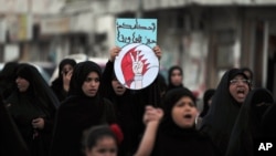 FILE - A Bahraini anti-government protester carries a sign with the words, "Oh, jailer, your sentences will not frighten us," during a march in the western village of Malkiya, Bahrain, October 3, 2013.