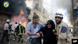 FILE - This photo taken June 8, 2016, and provided by the Syrian Civil Defense Directorate in Aleppo province, shows Syrian civil defense workers helping an injured woman after warplanes attacked a street, in Aleppo, Syria.