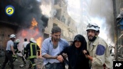  Un membre de la défense civile syrienne aide une habitante après que la ville a été frappée par une bombe aérienne à Alep, le 8 juin 2016, photographie prise par la Direction de la défense civile syrienne.